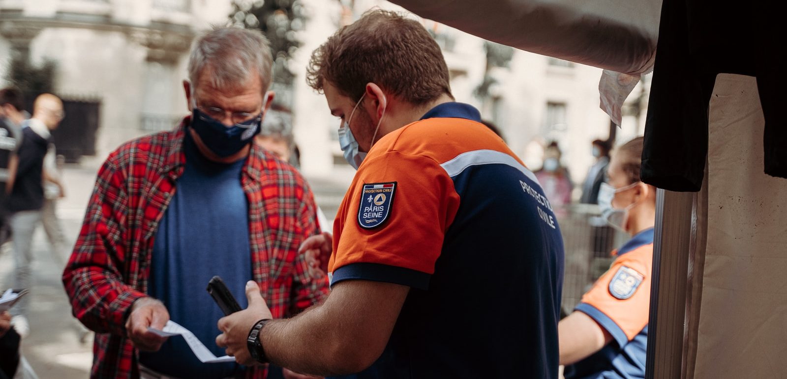 man in blue and orange polo shirt holding black smartphone